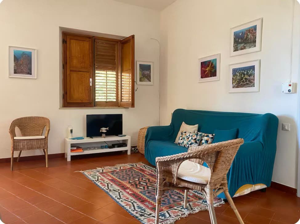 Wohnraum mit Sofa, Teppich und Korbsesseln